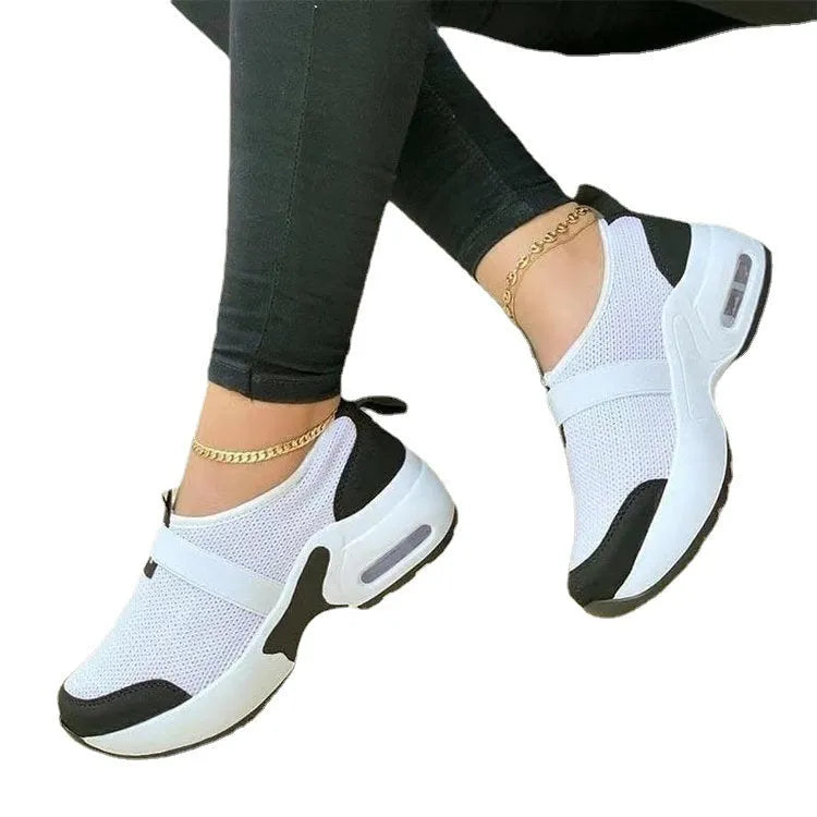 Women's white mesh flat sneakers with a rubber sole shown from the side.