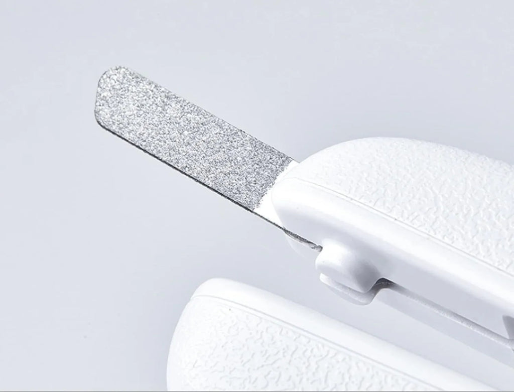 White pet nail clippers with LED light, anti-splash guard, and built-in file on a grey surface