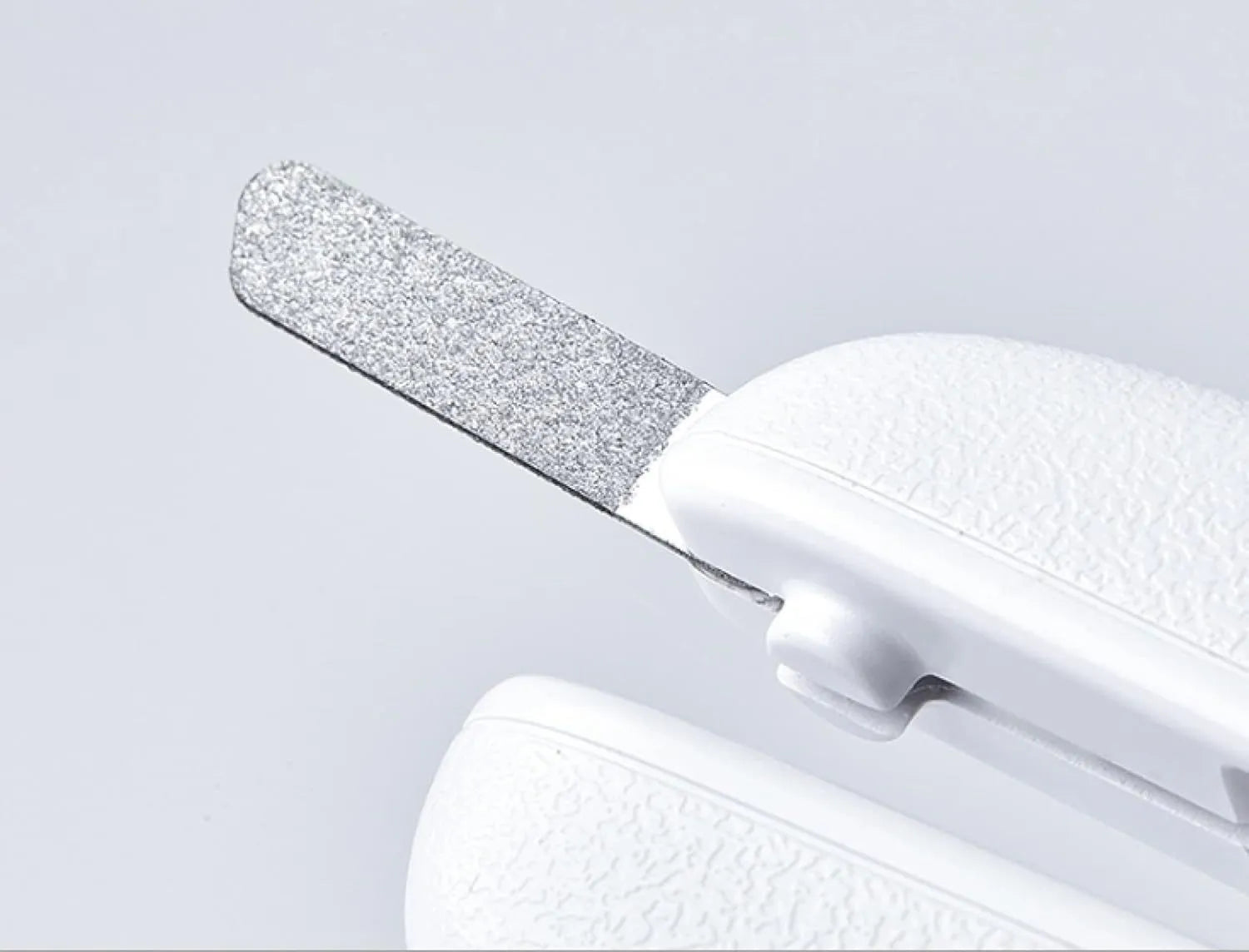 White pet nail clippers with LED light, anti-splash guard, and built-in file on a grey surface