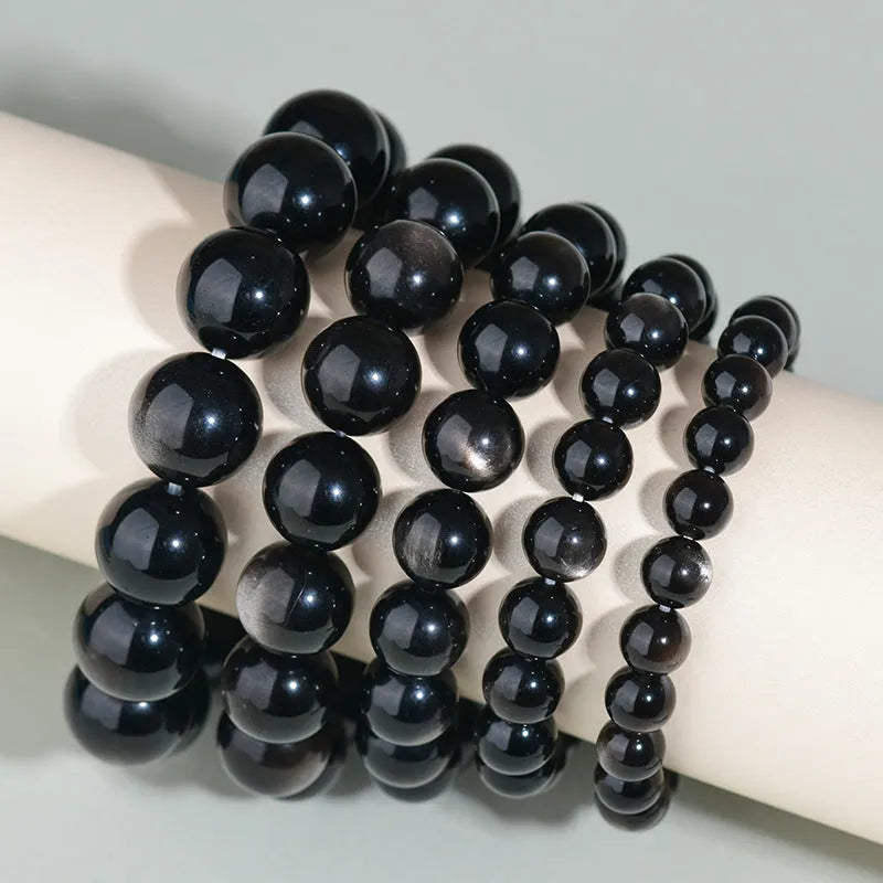 Hand-woven round obsidian bead bracelet in multiple colour options on a wrist.