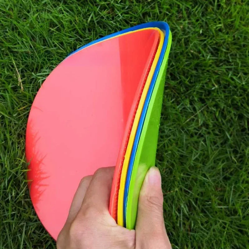 Flat, round yellow football training target disc with 23cm diameter on grass.