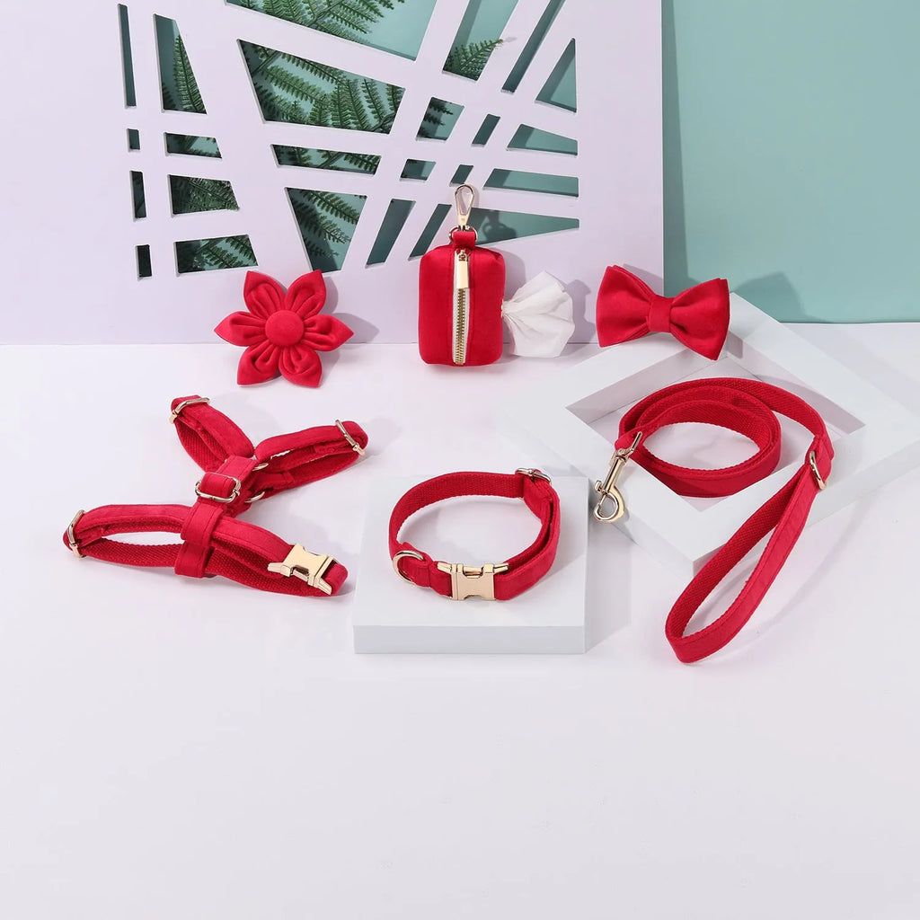 Red velvet dog collar and leash set with chest strap, bow tie, and decorative flower accessories.