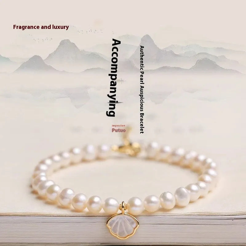 Women's freshwater pearl fan bracelet with alloy shell on wrist, showing elastic and chain closure options.
