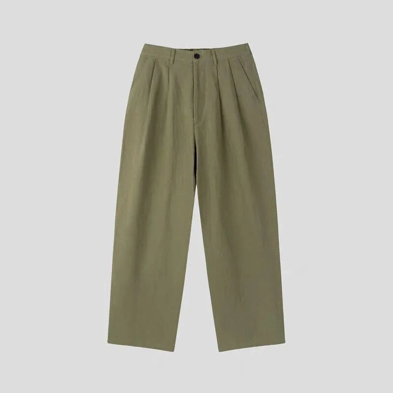 Man wearing apricot coloured loose wide-leg cotton linen trousers with a pencil leg opening.