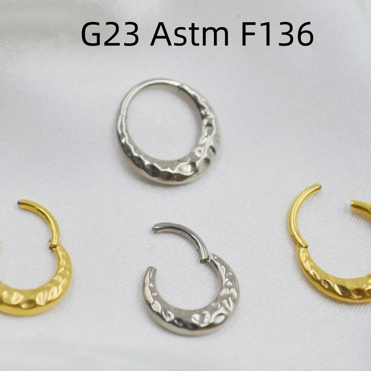 Titanium alloy concave-convex nose ring in gold and silver finishes showing surface texture detail
