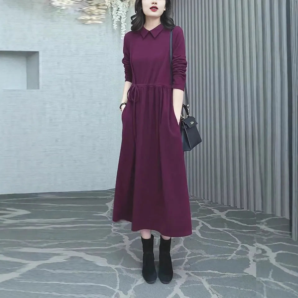 Purplish red plus size long sleeve dress for women with a long skirt, shown on a hanger.