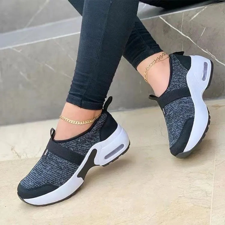 Women's white mesh flat sneakers with a rubber sole shown from the side.