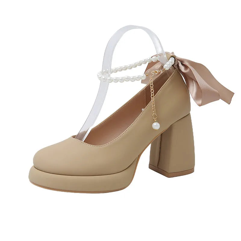 Women's beige Mary Jane shoes with chunky low heel, pearl decoration, and ankle strap buckle on a round toe.