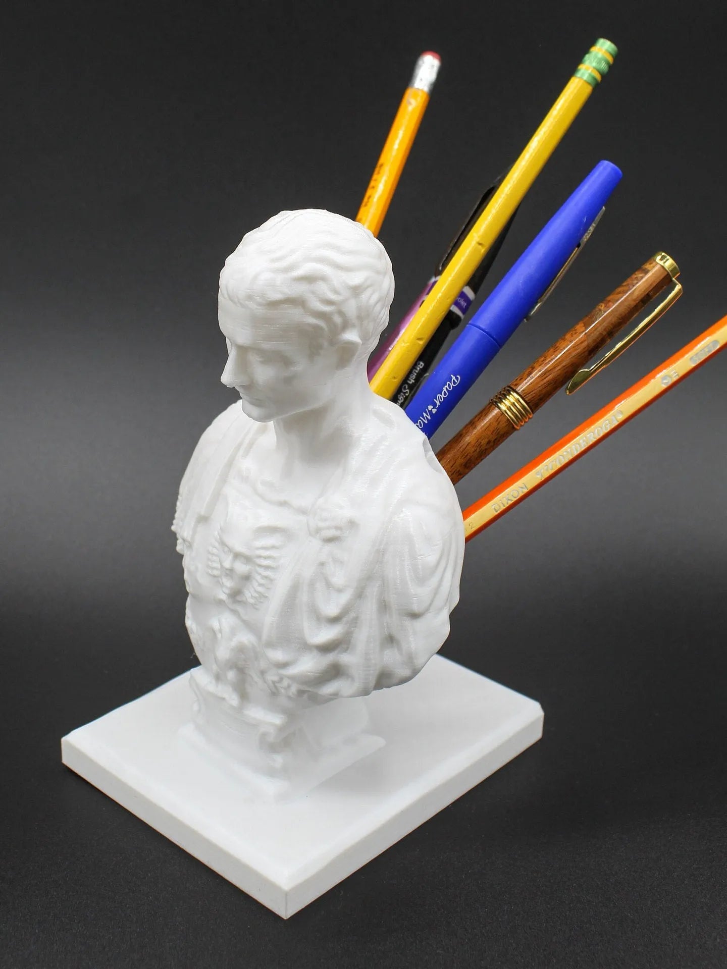 White synthetic resin pen holder with sculpted American creative character design on a desk.