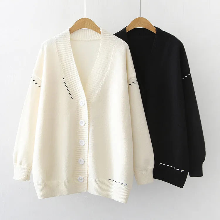 Women's loose fit black knitted cardigan top coat with long sleeves, hanging on a hanger.