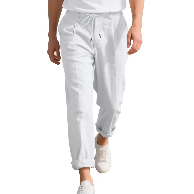 Men's straight leg linen trousers in light khaki colour with drawstring waist, laid flat.