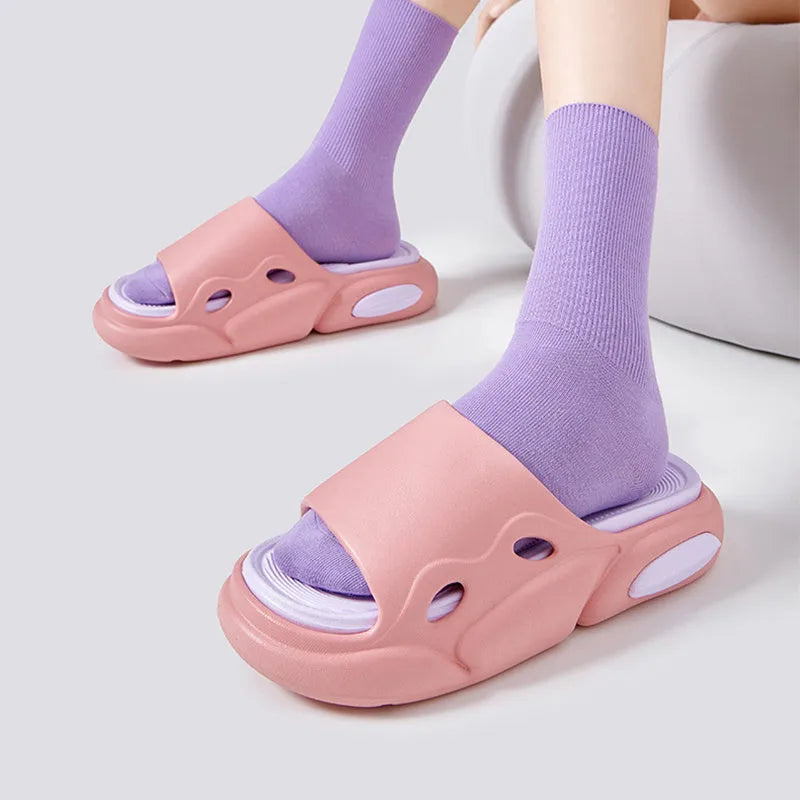 Two-colour EVA slippers for couples in pink and purple, shown on a wooden floor.