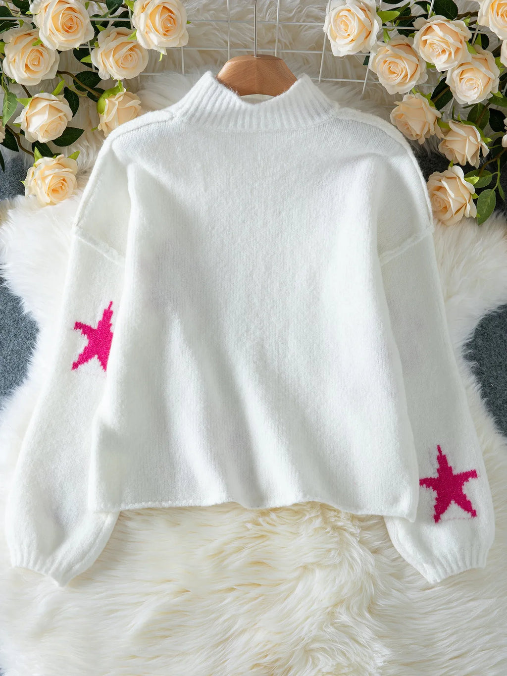 White women's loose turtleneck pullover with a black five-pointed star pattern on the front, made from thick polyester fabric.