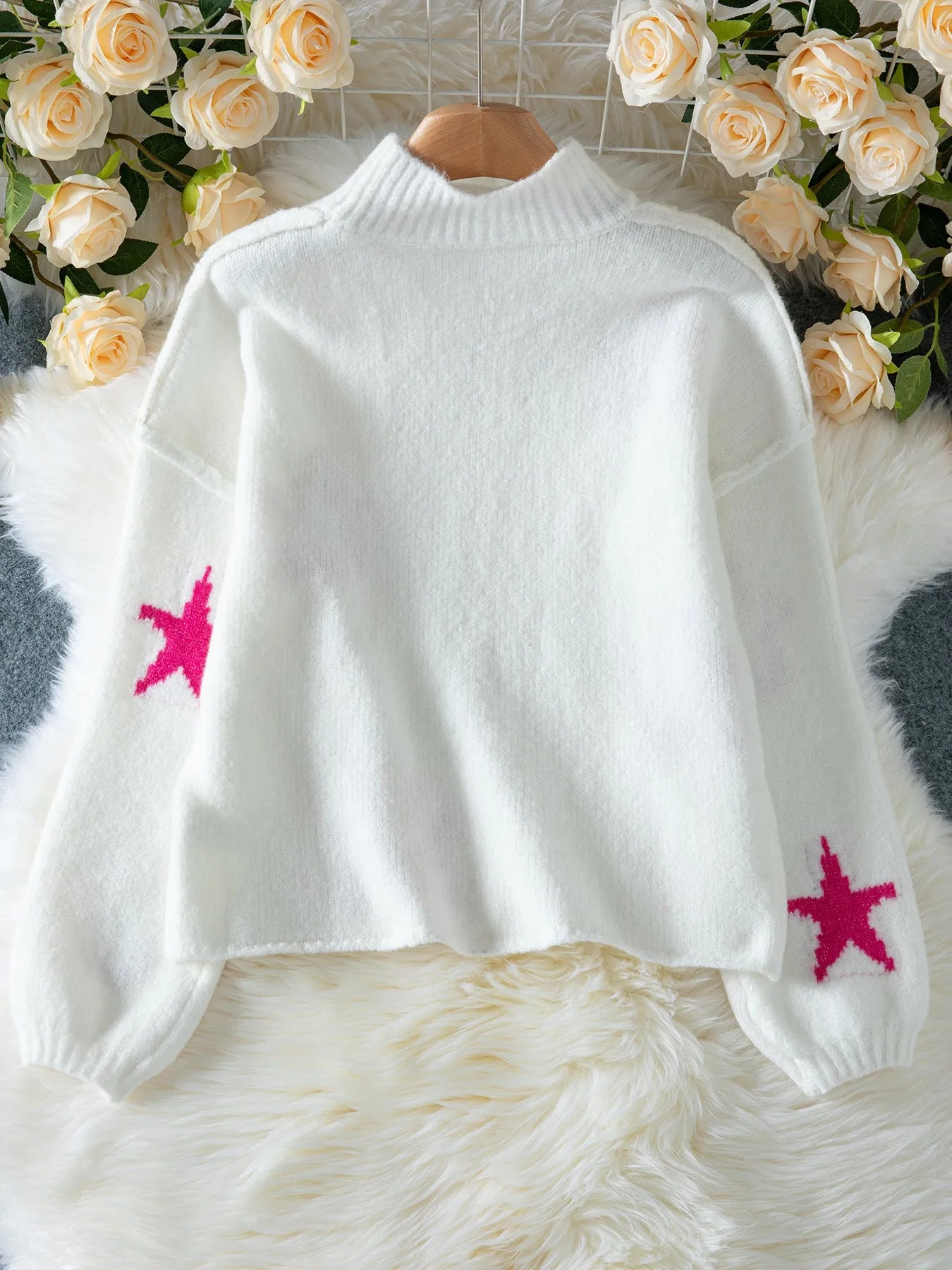 White women's loose turtleneck pullover with a black five-pointed star pattern on the front, made from thick polyester fabric.