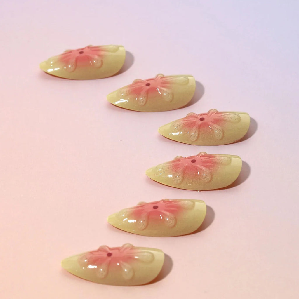 Set of pink cartoon flower fake nails with wearable armour, jelly glue, and file on a white background.