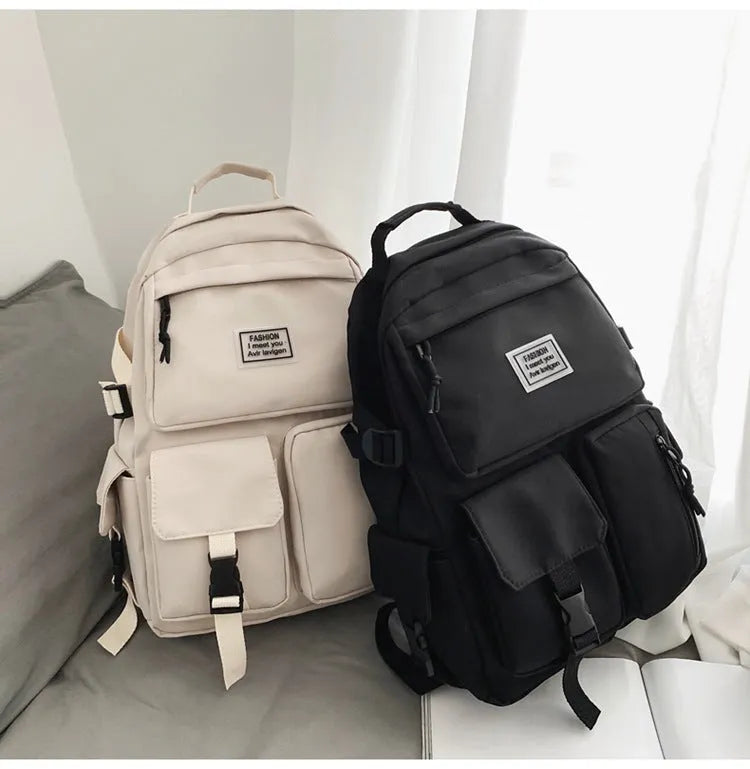 Black and white nylon student backpack with front 3D pockets, shown with laptop in compartment.