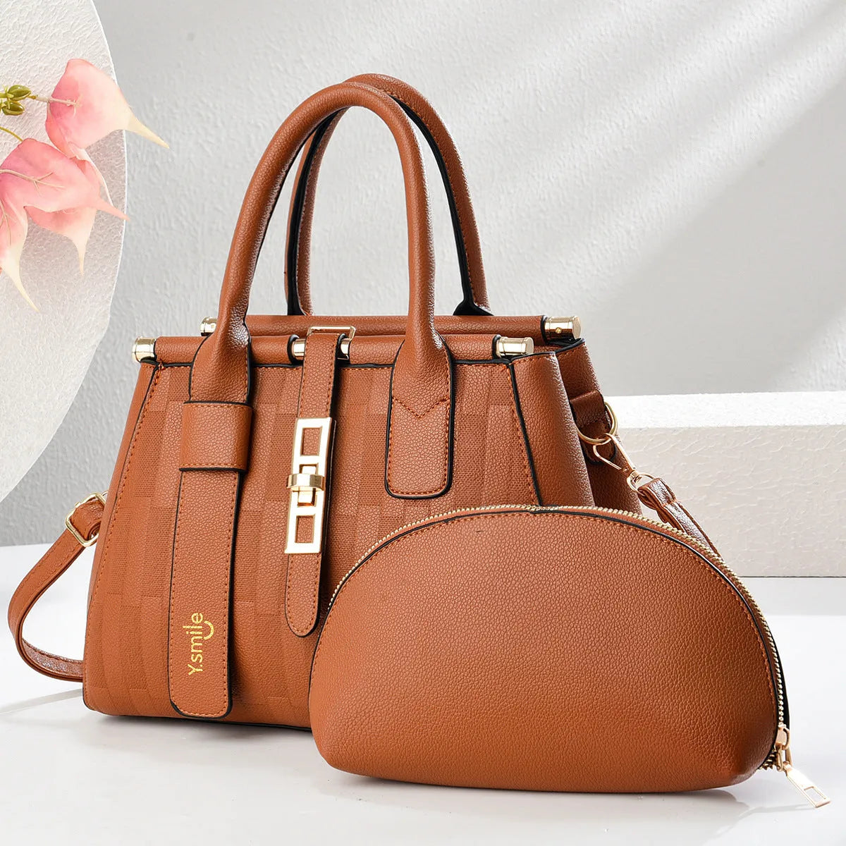 A pair of round black and light khaki PU leather crossbody bags with adjustable straps.