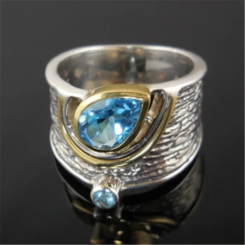 Blue zircon drop shape ring with Chinese style inlaid design on alloy band.