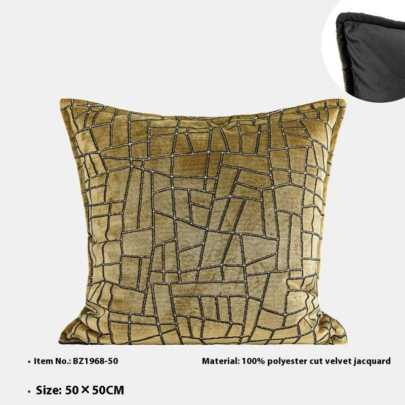 Geometric abstract pattern decorative pillow case in gold colour on a grey sofa.