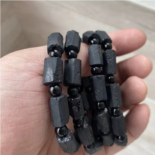 Black tourmaline rough stone bracelet with unpolished beads on a wrist.
