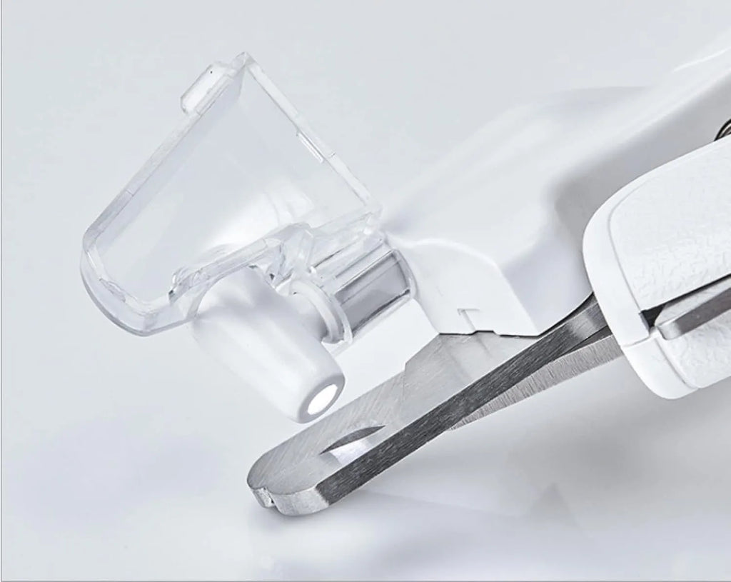 White pet nail clippers with LED light, anti-splash guard, and built-in file on a grey surface