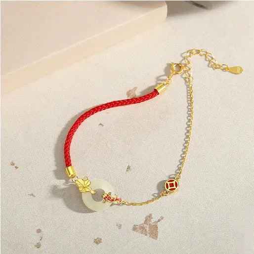 Women's red rope bracelet with silver and gold peace buckle charm featuring koi fish design