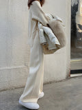 Women's cream white high waist wide-leg knitted trousers with a long mopping hem and elastic waistband.