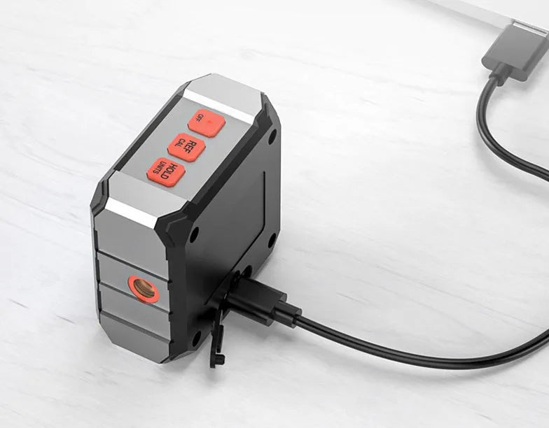 Digital laser infrared tape measure inclinometer with alloy casing and backlit display on a metal surface.