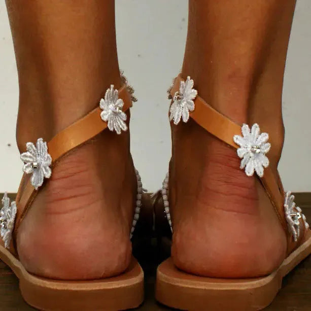 Brown women's flat Roman sandals with a herringbone toe design and ethnic floral pattern on the straps.