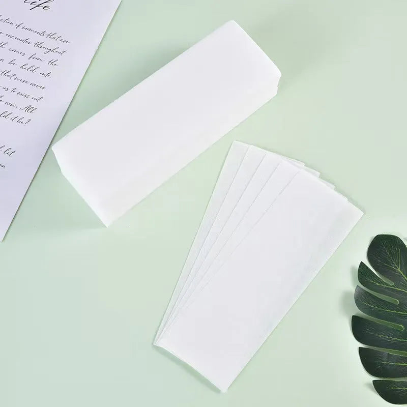 A pack of soft, white non-woven fabric hair removal wax paper strips.