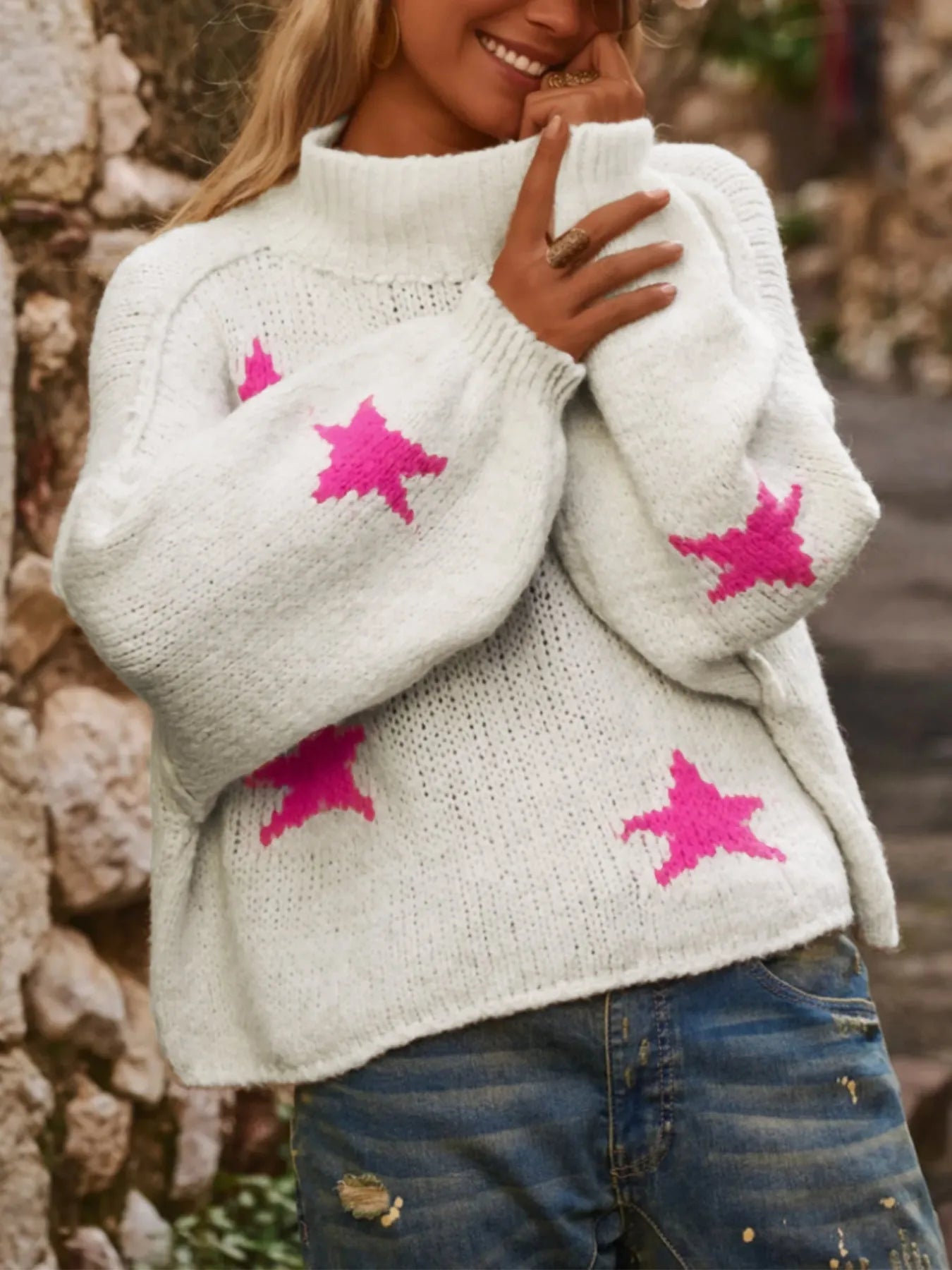 White women's loose turtleneck pullover with a black five-pointed star pattern on the front, made from thick polyester fabric.