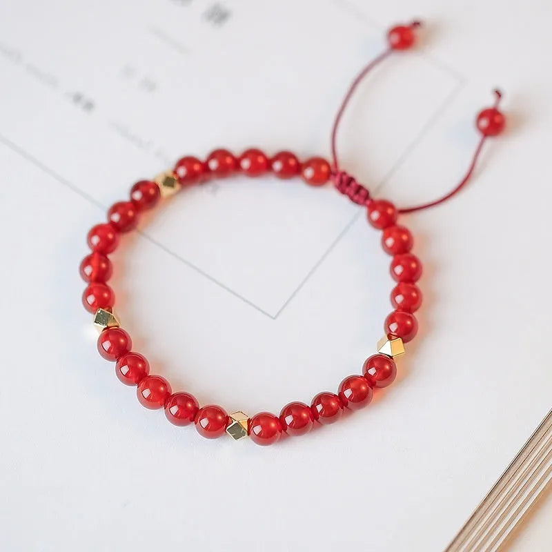 Hand-woven red agate bead bracelet with ethnic design on a wrist.
