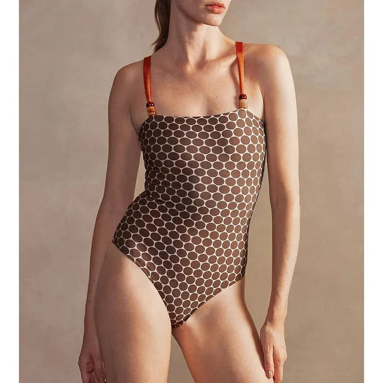 Women's printed dot pattern one-piece swimsuit with matching wrap skirt on a hanger.