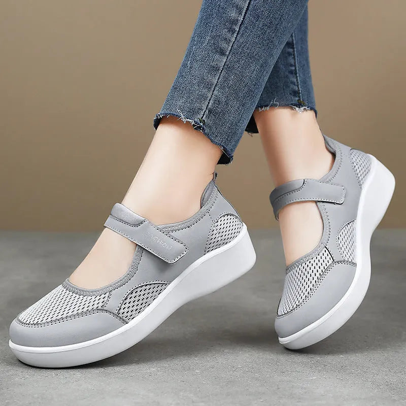 Women's grey mesh slip-on casual shoes with Velcro strap fastening on a flat sole.