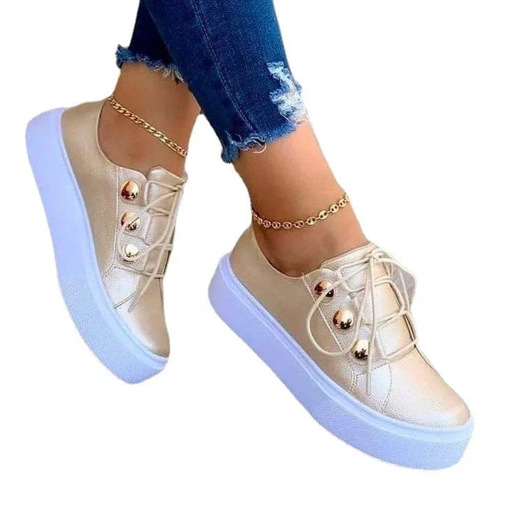 Women's white lace-up flat sneakers with silver rivet detailing on a round toe.