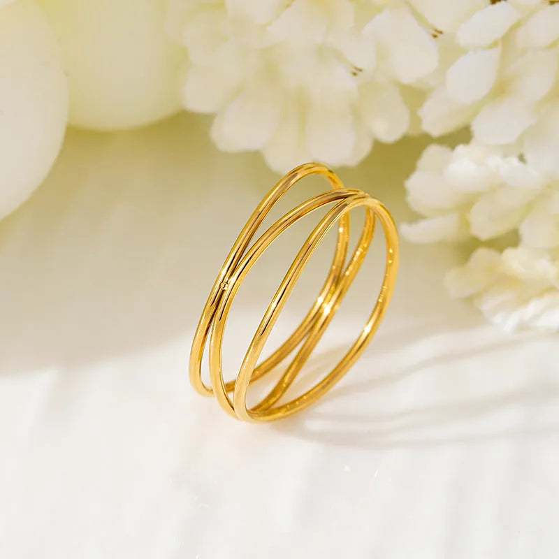 Gold geometric line ring with three-layer coil design on finger