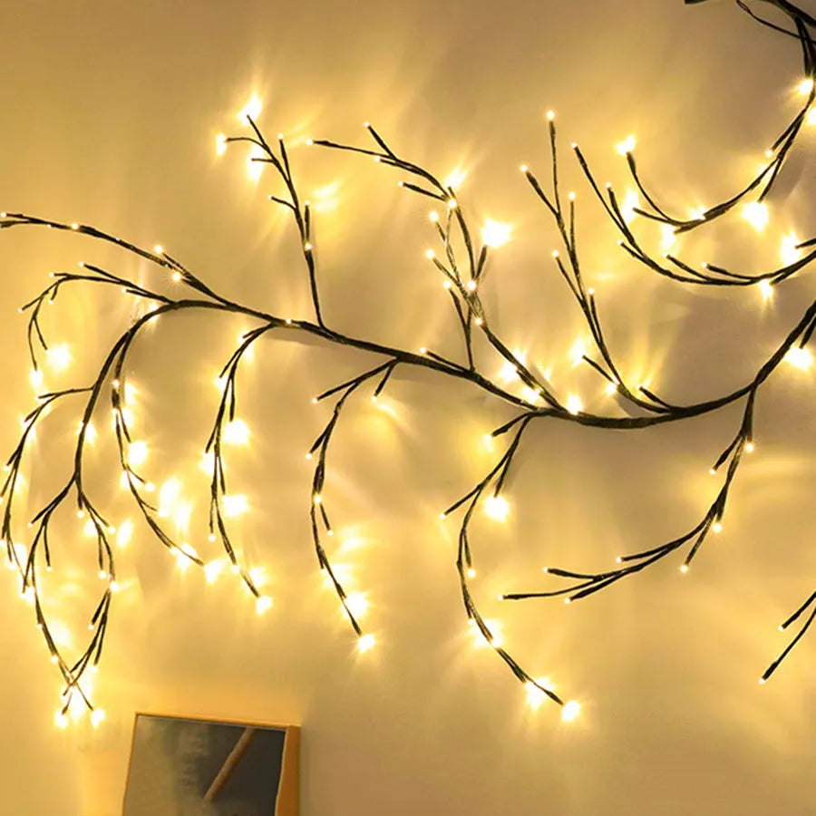 Flexible LED willow vine garland with warm white lights on birch-textured branches for wall and party decor.