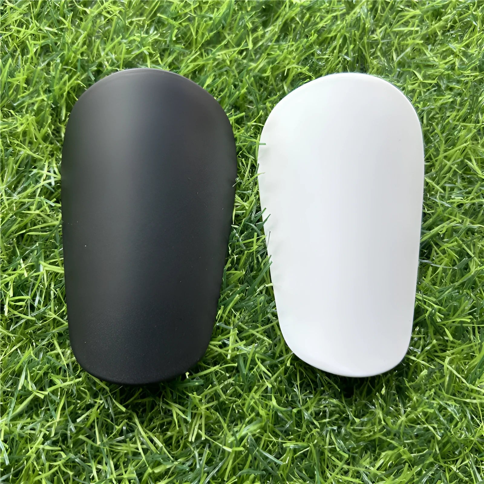 Pair of extra small black and white plastic football shin guards measuring 8x5cm for youth players
