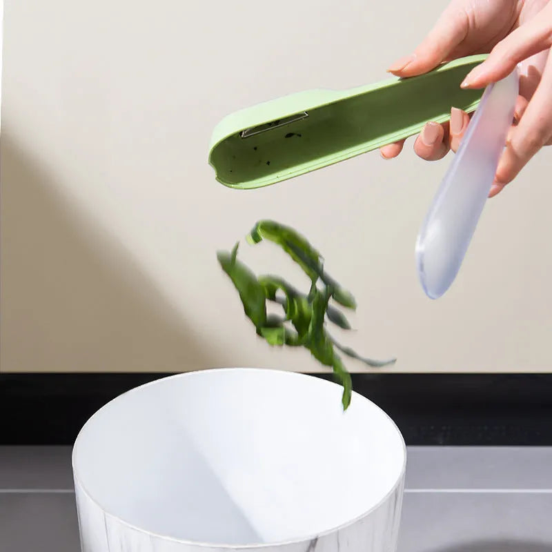 Dark green kitchen peeler with stainless steel blade inside a storage tube