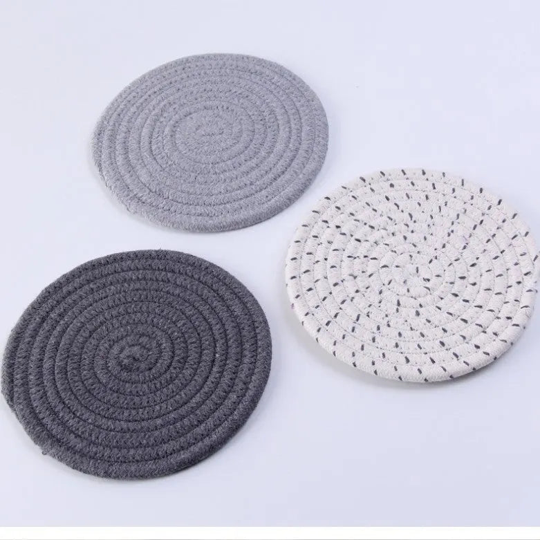 Set of three round grey cotton cord coasters on a wooden table, each 18cm in diameter.