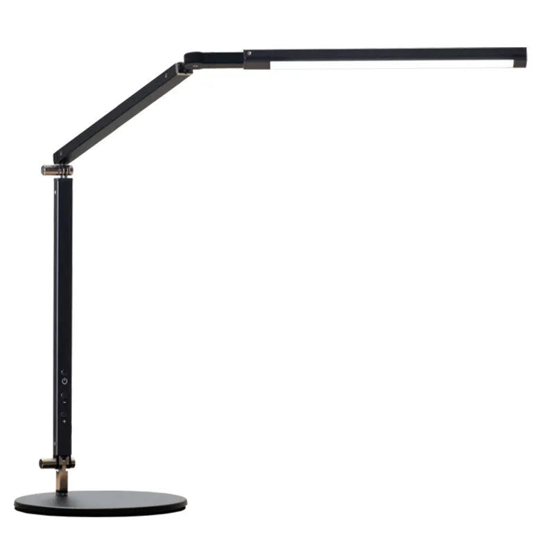 Folding aluminium desk lamp with a metal clip, shown in dazzling black, attached to a desk edge.