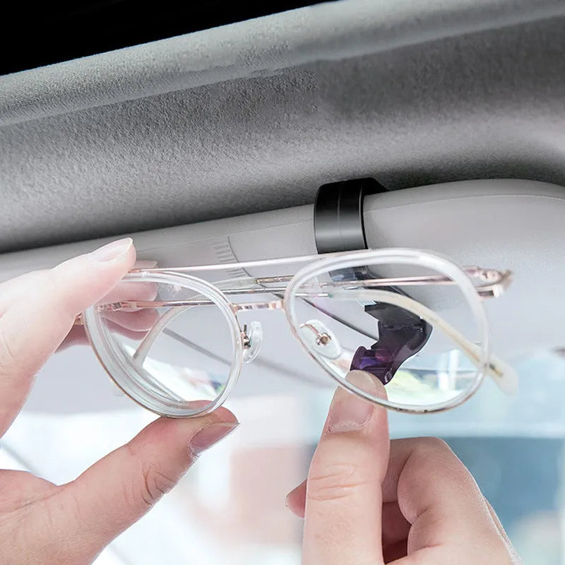 Black plastic car sunshade clip holding sunglasses and parking ticket