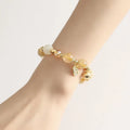 Gold rutilated quartz bracelet with bell charm on wrist