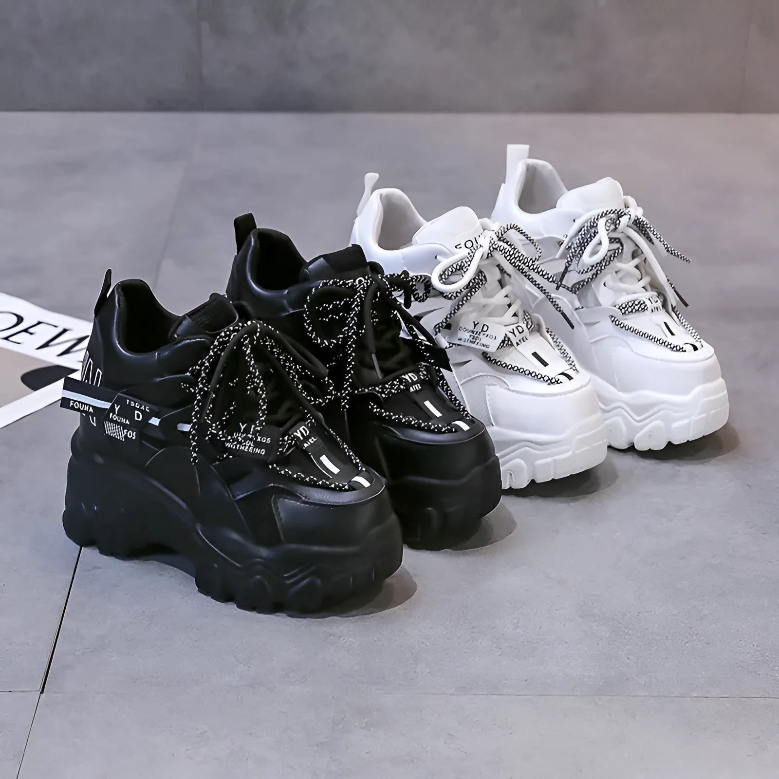 White and black women's mesh platform sports shoes with cross-strap and rubber sole.