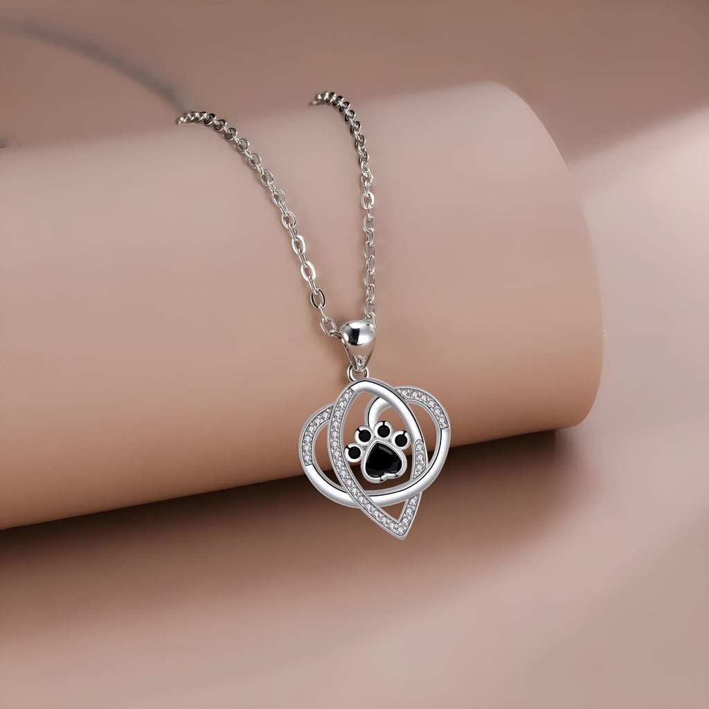 Copper pendant necklace showing a detailed cat and dog paw print design on a cross chain.