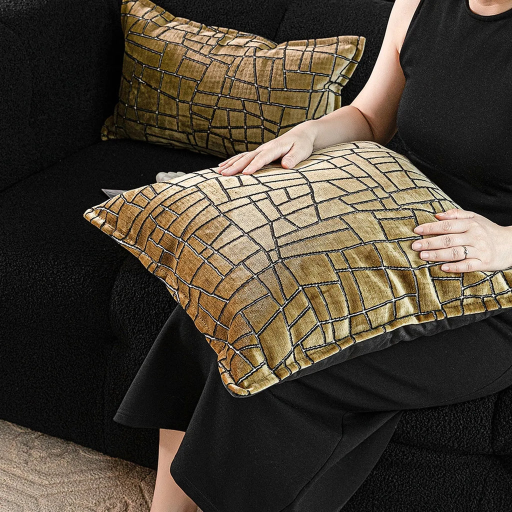 Geometric abstract pattern decorative pillow case in gold colour on a grey sofa.