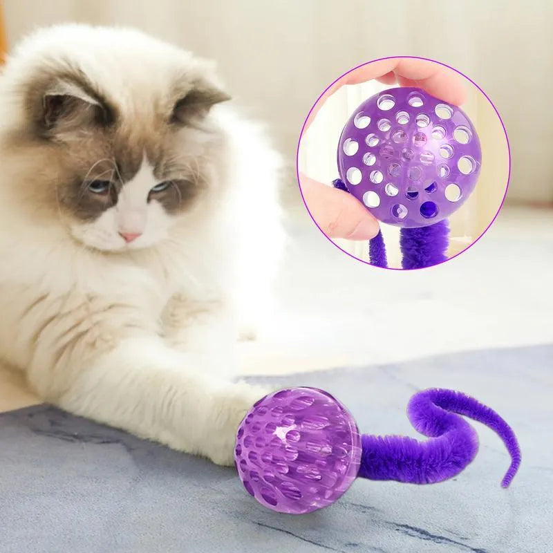 Green interactive cat toy featuring a bouncy ball with a long plush tail on a wooden floor.