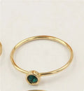 Women's 14K gilded gold-filled zircon copper knuckle ring in green, blue, dark red, or white on a finger.