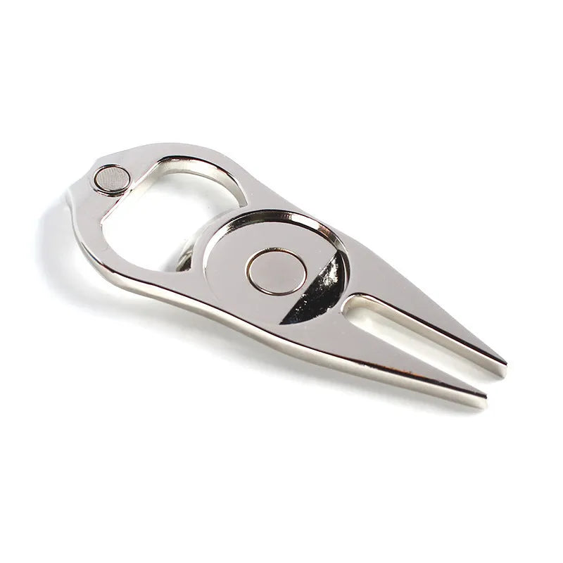 Black zinc alloy golf ball fork and bottle opener tool on green turf