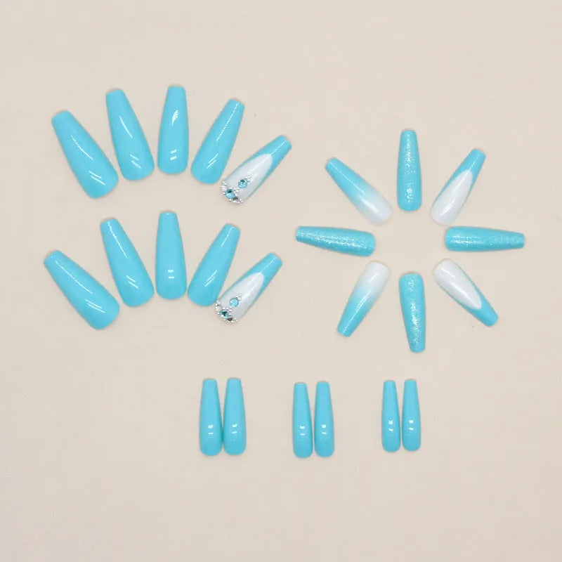 Long ballet shaped artificial nail patches with blue diamond glitter on a solid colour background, shown with a bottle of nail glue.